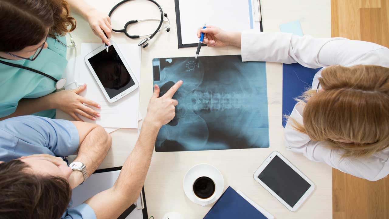 doctors look at x-ray image which a medical interpretations expert can convey to the patient